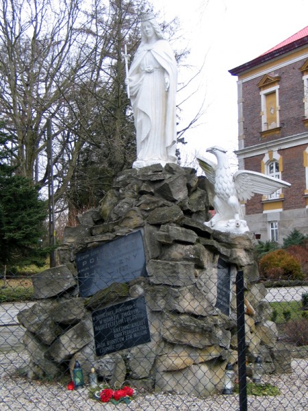 Figura Matki Boskiej Kr&oacute;lowej Polski w zespole d. Krajowej Niższej Szkoły Rolniczej w Miłocinie (1926 r.) umieszczona na kamiennym kopcu poświęconym pomięci uczni&oacute;w Szkoły Rolniczej, kt&oacute;rzy polegli w obronie ojczyzny w latach 1914-1920